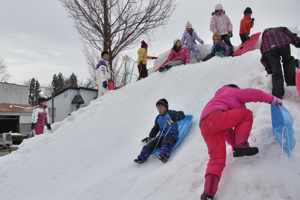 雪のすべり台をすべる子どもたちの画像