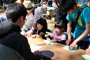 紙ひこうきをつくる来場者の画像