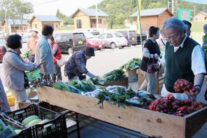 野菜を買い求めるお客さんの画像