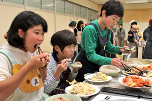 できた料理を食べる児童の画像