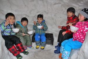 かまくらの中でお餅を食べる子どもたちの画像