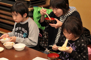 伸びる餅を食べている来場者の画像