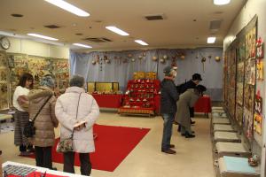 2階旧食堂に展示されているお雛様と絵紙を観覧する人の画像