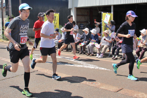 力走する参加者を沿道から応援する地元の方の画像