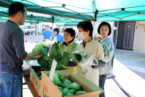 野菜を買い求めるお客の画像