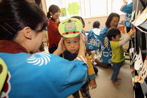 おめんをかぶせてもらう子どもの画像