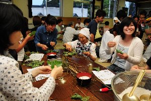 地元の高齢者から作り方を教わる参加者の画像