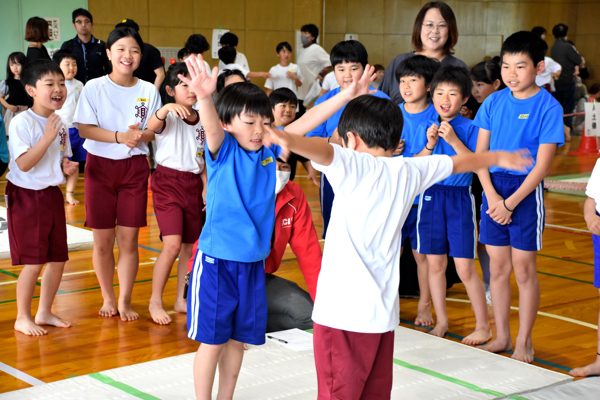 手押し相撲をする男の子と応援する子どもたちの画像