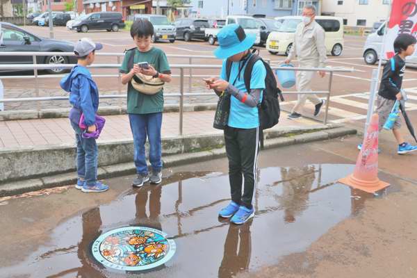 錦鯉の里でポケふたを撮影する子どもたちの画像