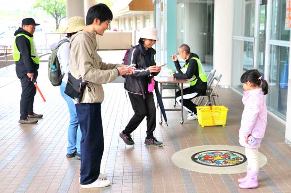 総合体育館のポケふたの前で記念撮影する参加者の画像