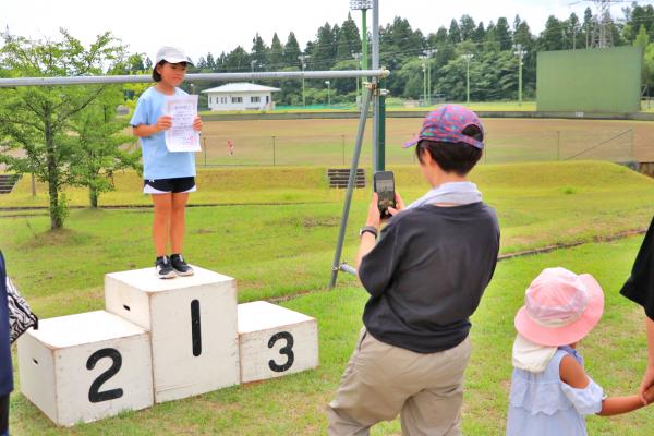 表彰台で記念撮影する親子の画像