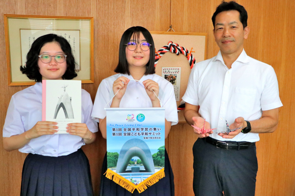 中学校二人と並んで折り鶴を持つ市長の画像
