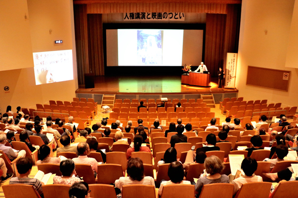 162人の参加者が講演を聞いている画像