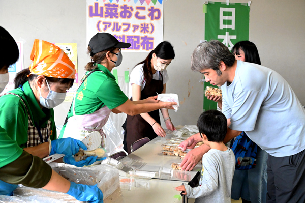 ゴール会場で無料配布の山菜おこわを受け取る参加者の画像
