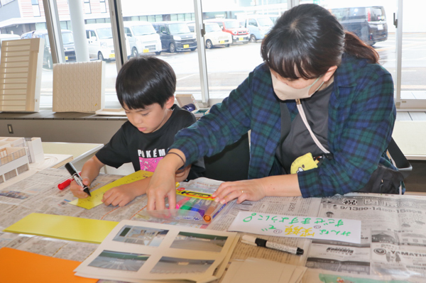 マジックペンでマグネットシートにメッセージを書く親子の画像