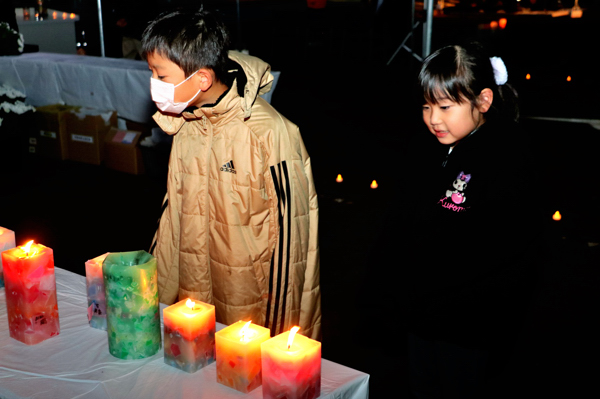 希望のキャンドルの灯りを眺める2人の子どもの写真