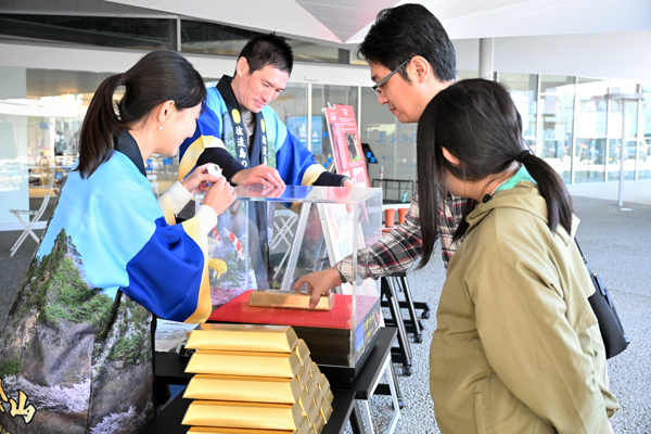 金塊つかみ体験にチャレンジする親子の画像