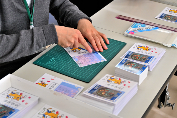 合格祈願！マンホールカードを作成している職員の画像