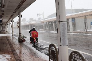雪の中、配達をする郵便局員の画像
