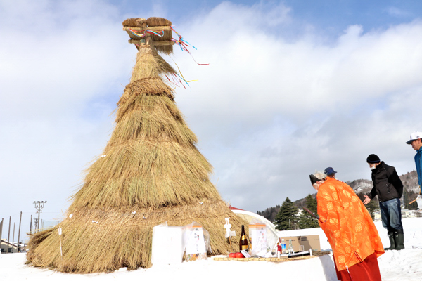 さいの神で点火前におはらいをする女性の画像