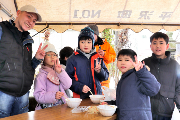 豚汁を一緒に食べる子どもたちと大人の画像