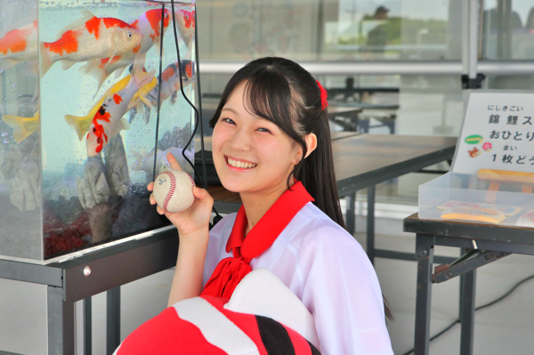 錦鯉の水槽と並んで笑顔を浮かべる北村優羽さんの画像