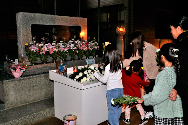 追悼のつどいで献花をする親子の画像