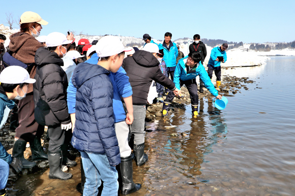 放流の仕方を教えてもらっている児童たちの画像