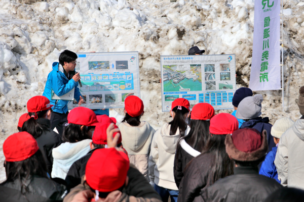 サケの一生についての説明を真剣に聞いている小学生の画像