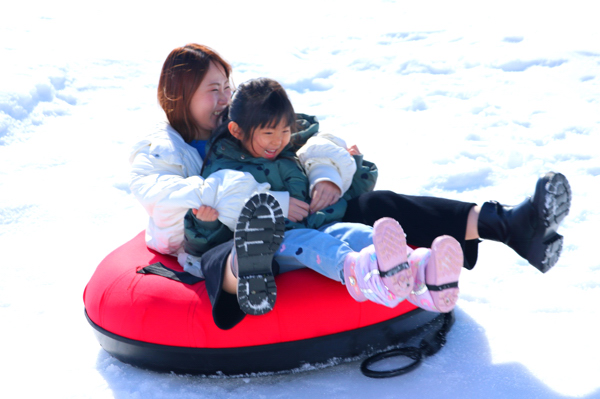 スノーチューブで遊ぶ親子の画像