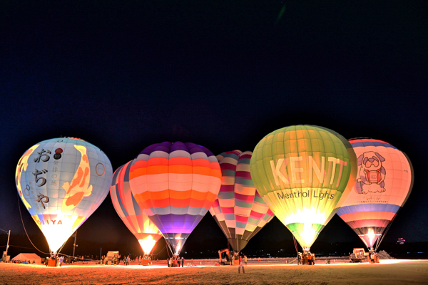 雪原に並んで点灯する6基の熱気球の画像