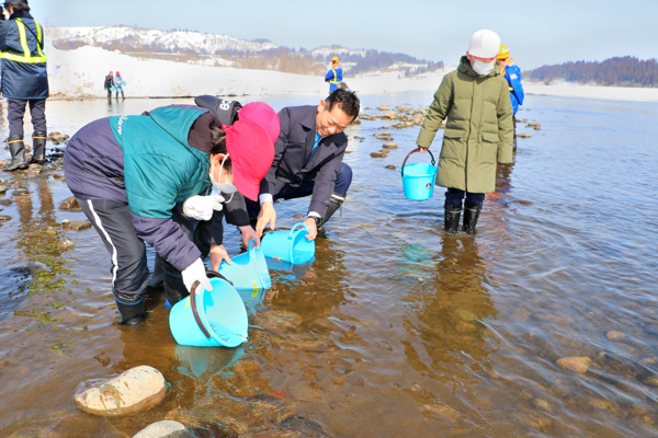 小学生と一緒に稚魚を放流する市長の画像