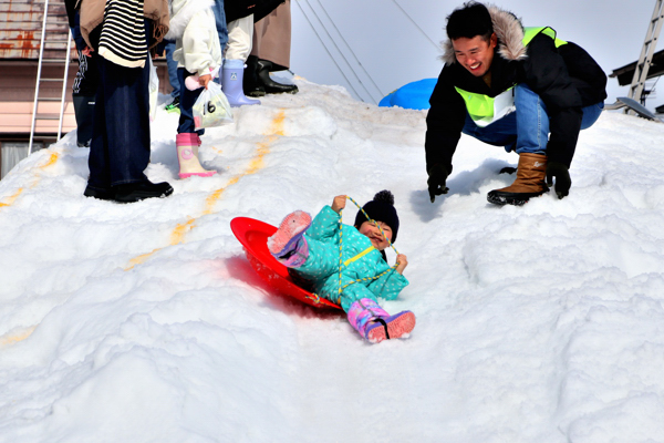 そりで雪山を滑る女の子の画像