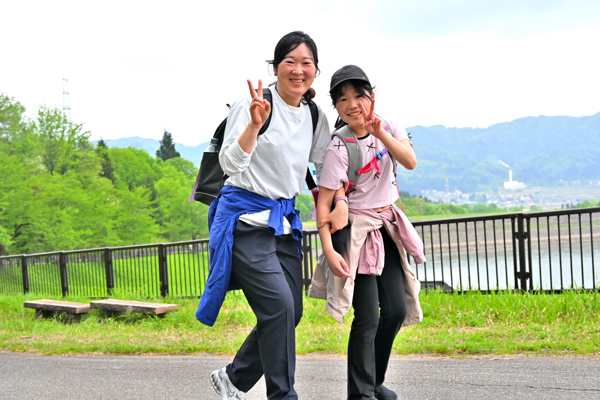 歩きながらピースサインをする親子の画像