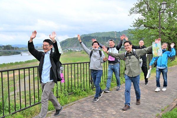 両手を上げて楽しそうに歩く男性グループの画像
