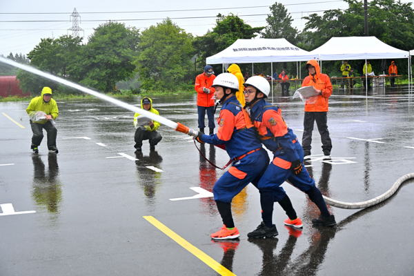 雨の中ポンプ操法訓練を行う小千谷市の消防団の画像
