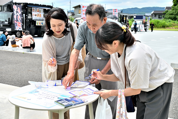 屋外のチェックポイントでスタンプを押す来場者の画像
