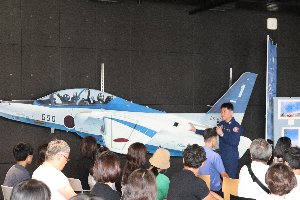 ブルーインパルスの模型の前で講演する江尻隊長の画像