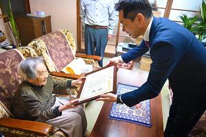 100歳の褒状を受け取る女性の写真