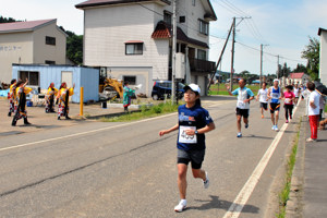 沿道の声援に応えながら走る選手の画像