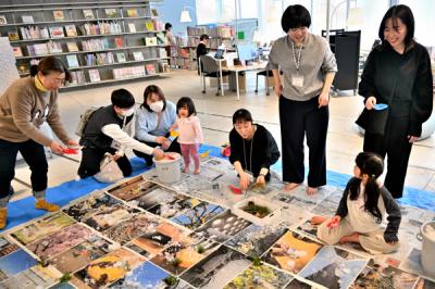 写真の上に雪を撒く参加者たちの画像